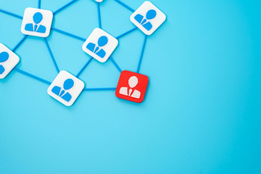 A network of person icons, with one red icon standing out from the blue ones, all connected by lines.