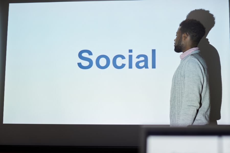 A man standing in front of a projection screen that says "Social."