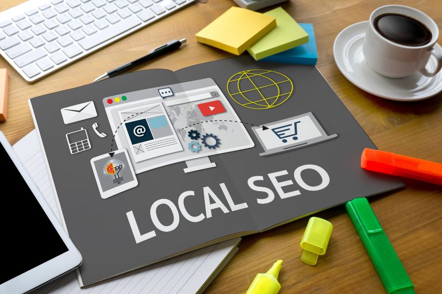 An open book on a desk with the words "LOCAL SEO" and related marketing icons on its pages.